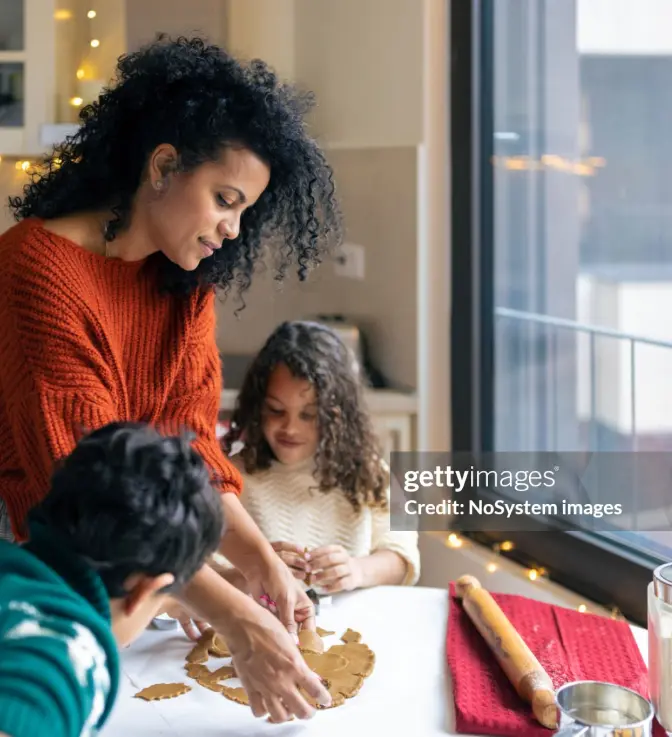 Family bakes cookies in the warmth of their home by a window.