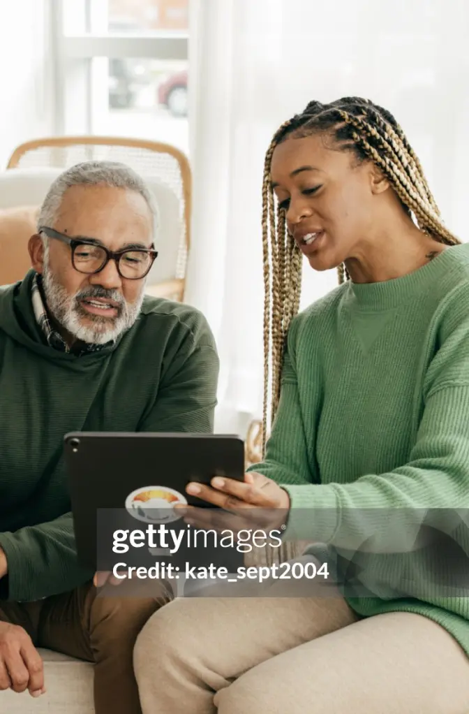 Father and older daughter look at a tablet together.